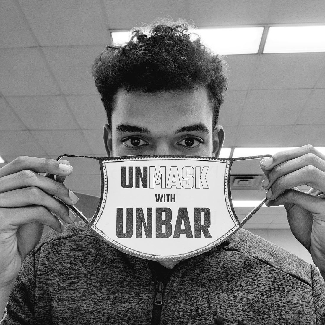 Black and white portrait of Ayden holding an Unmask with unbar mask